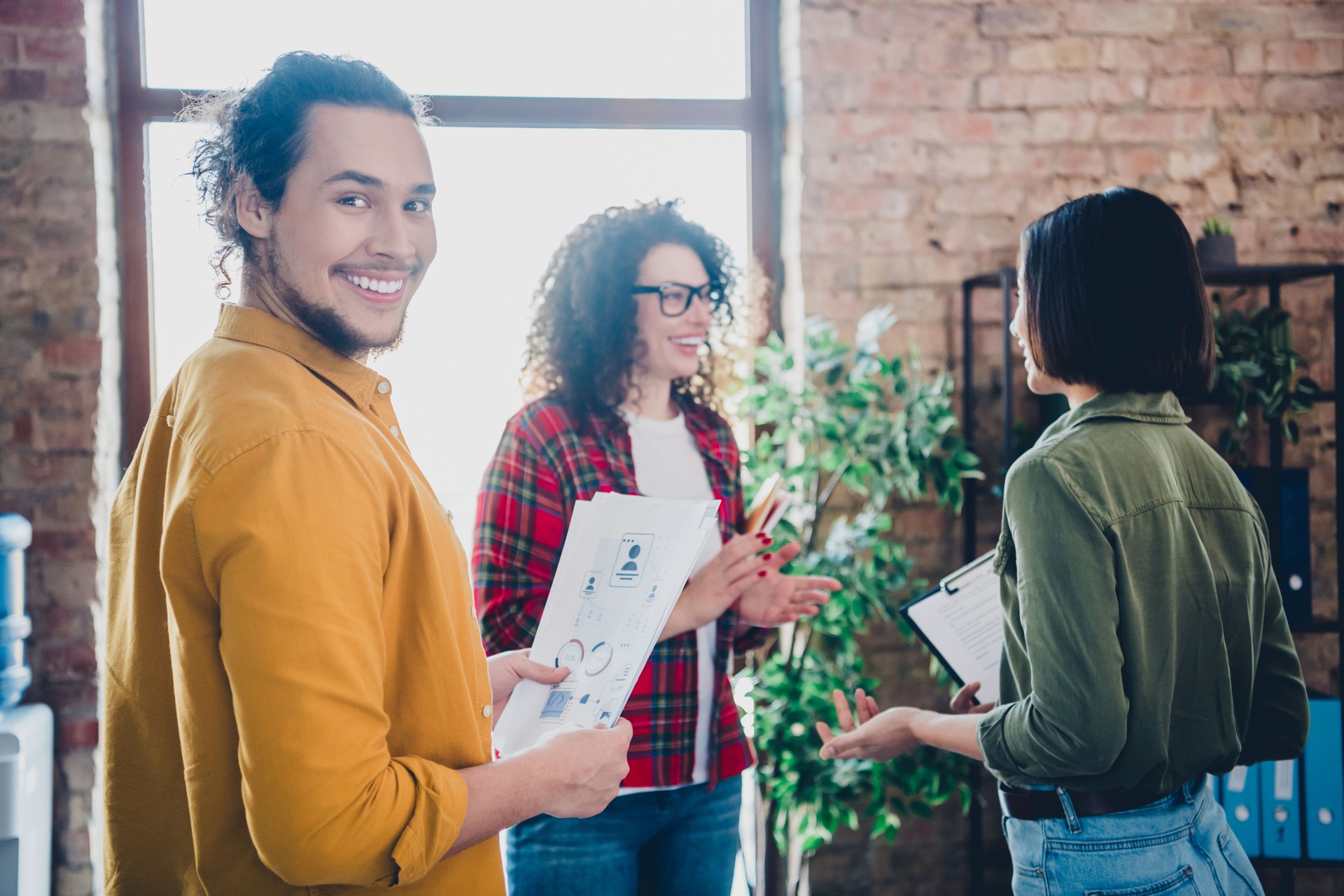 Casual coworkers collaborating in a sunny office, sharing ideas and teamwork, combining expertise for productive results