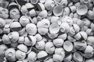 A large pile of white ceramic bowls and spoons stacked chaotically.