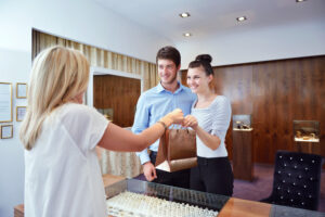 A couple receives a shopping bag from a store employee in a jewelry shop.